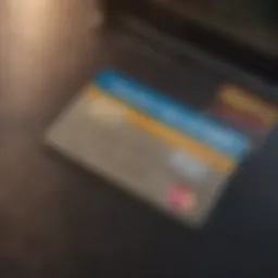 Close-up view of a credit card with a laptop in the background